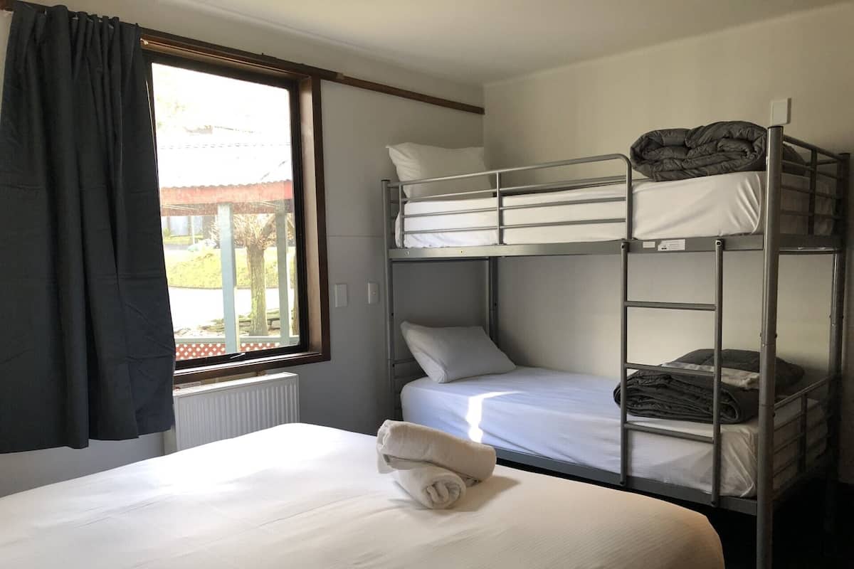 A bunk bed room with a window, a radiator, and a towel on the bed.
