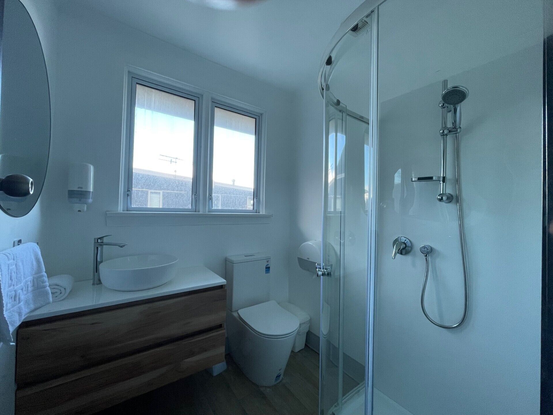 A modern bathroom with a glass shower enclosure, a white sink, and a toilet.