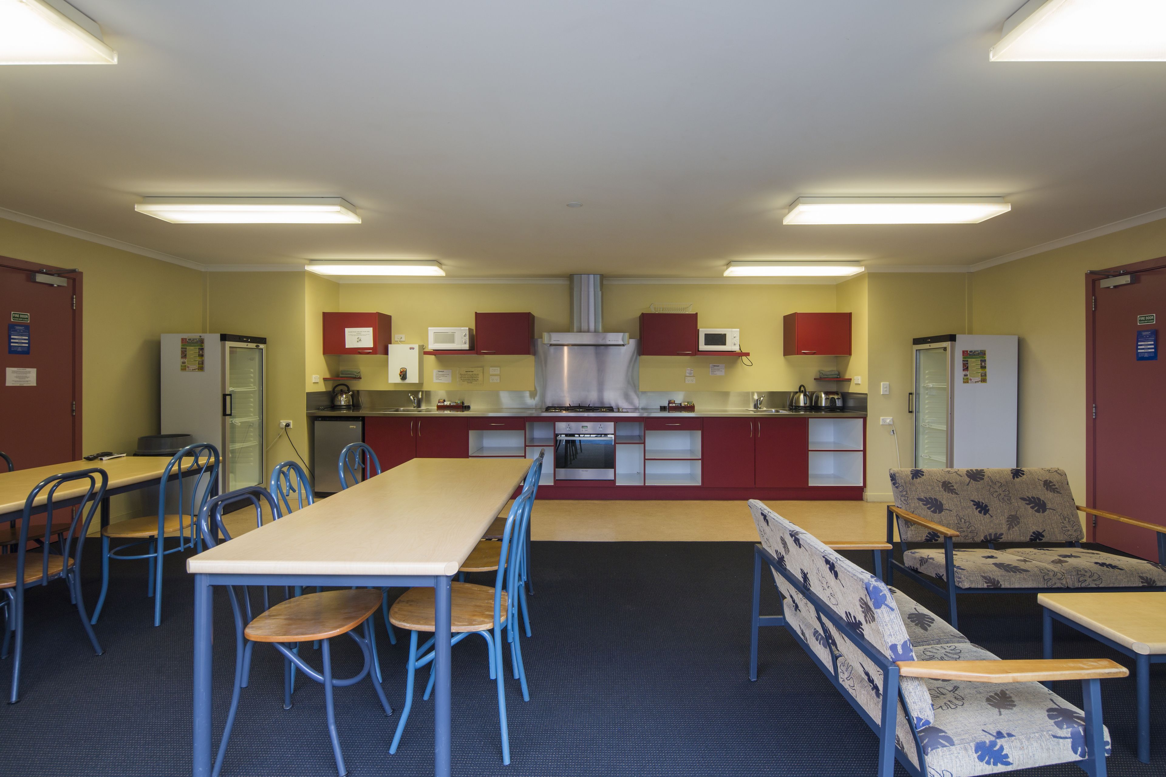 Un comedor con una mesa larga, sillas, un banco y una kitchenette equipada.