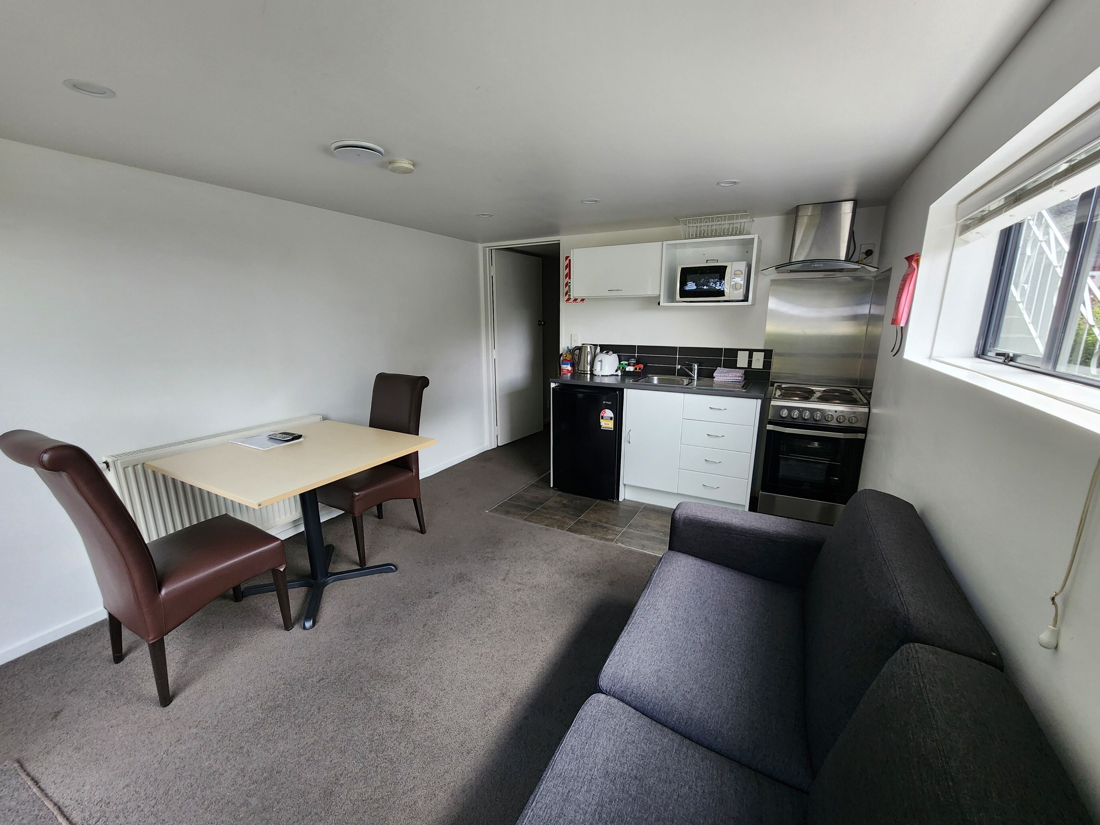 A compact living space with a kitchenette, a dining area with a table and chairs, and a sofa.