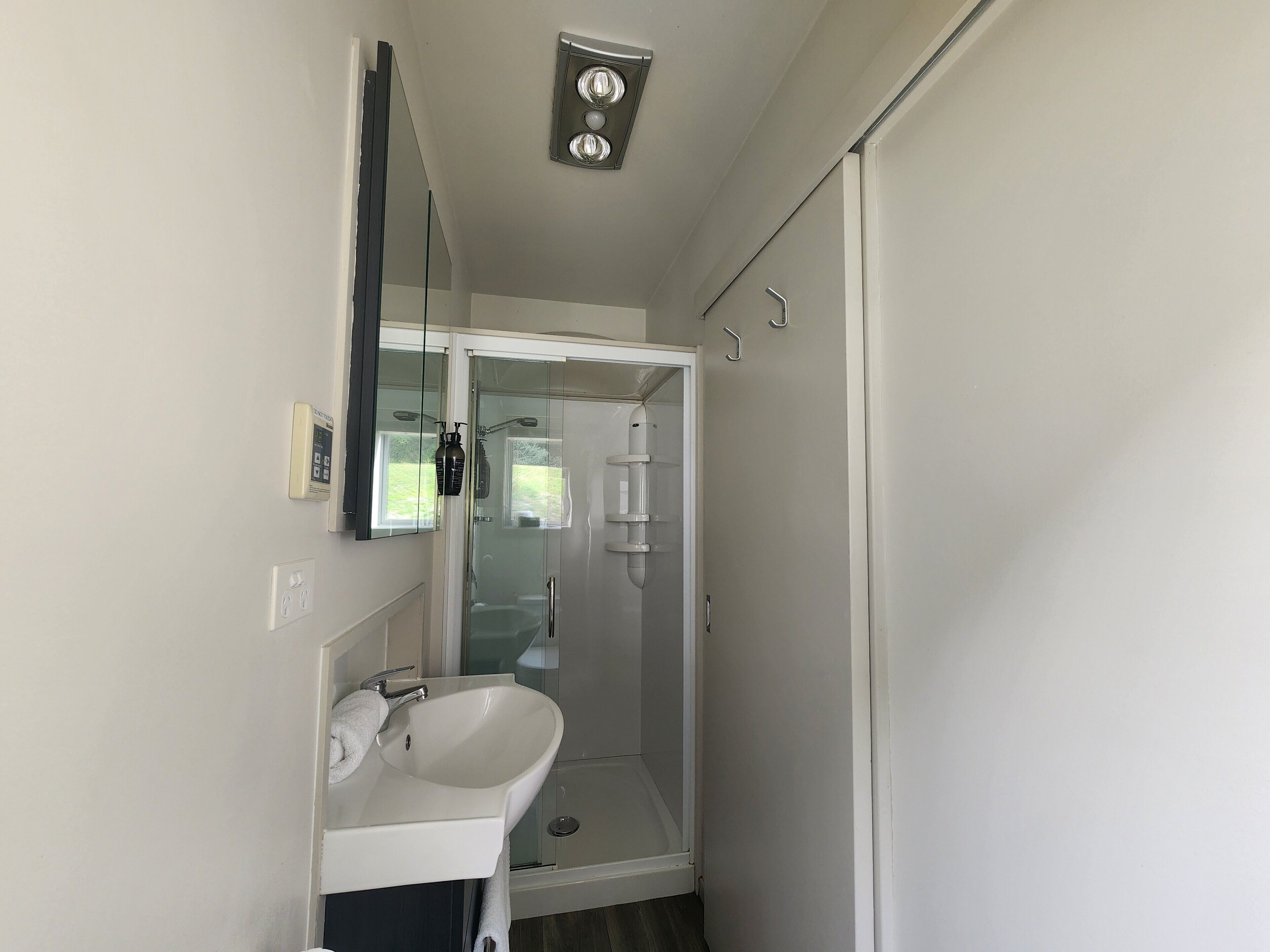 Un baño moderno con ducha de vidrio, lavabo blanco y espejo.
