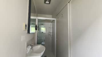 Un baño moderno con ducha de vidrio, lavabo blanco y espejo.