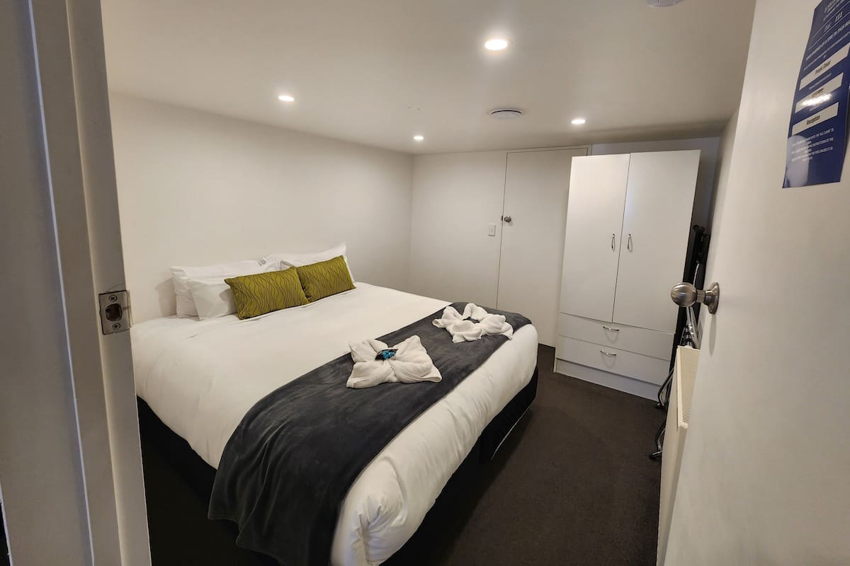 A hotel room with a bed, a wardrobe, and a door.