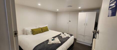Une chambre d’hôtel avec un lit, une armoire et une porte.