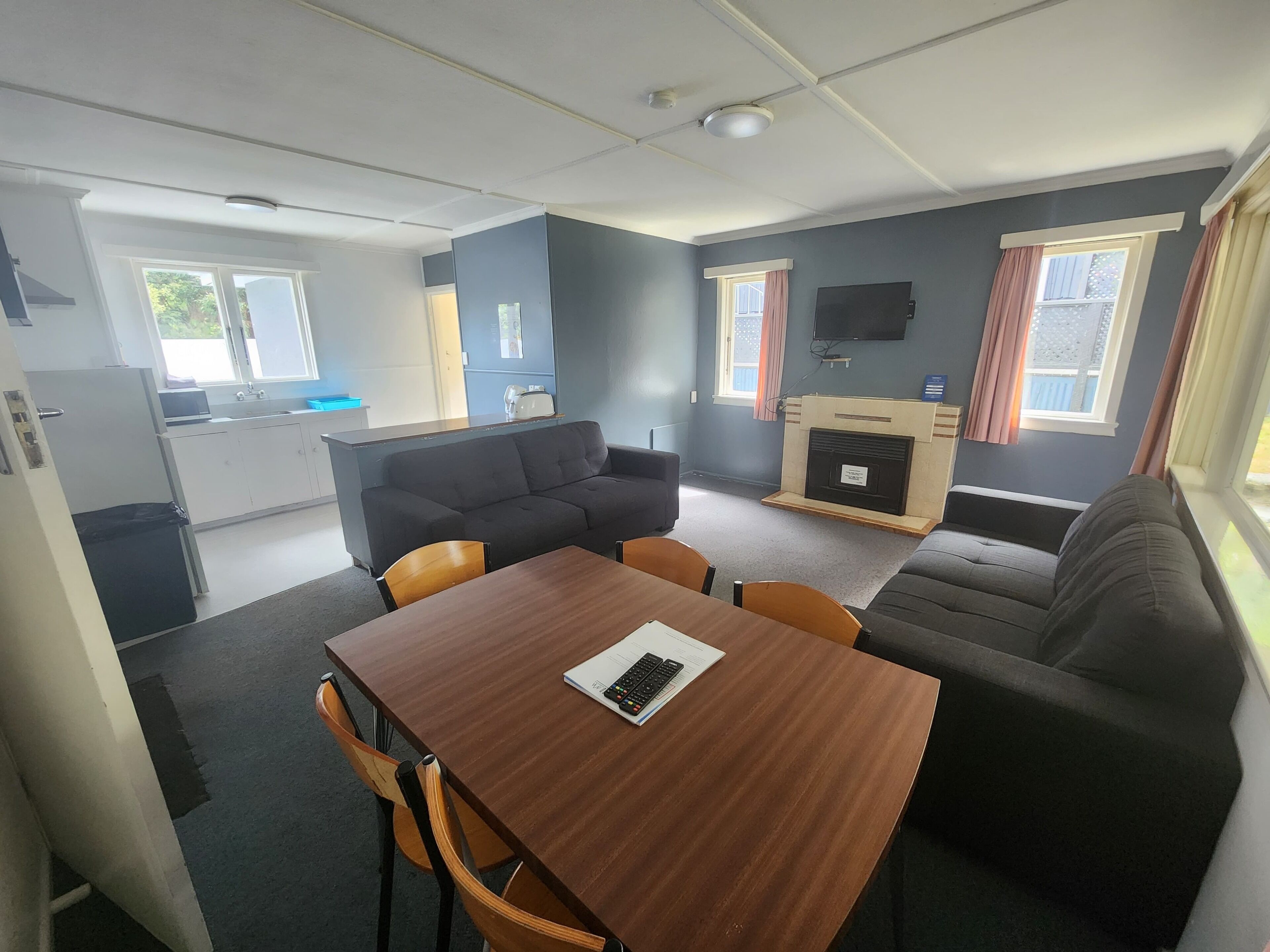 A compact living space with a kitchenette, a sofa, a dining table, and a fireplace.