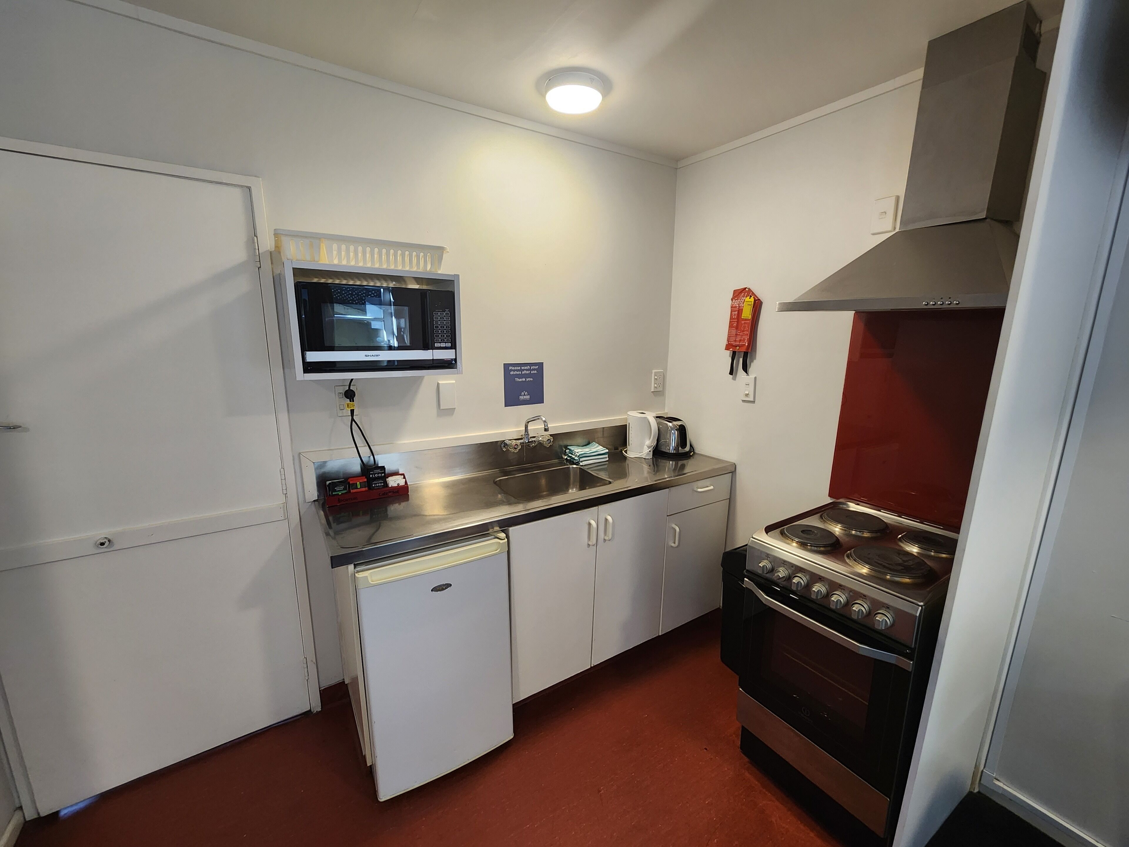 A compact kitchen with a microwave, sink, refrigerator, and stove.