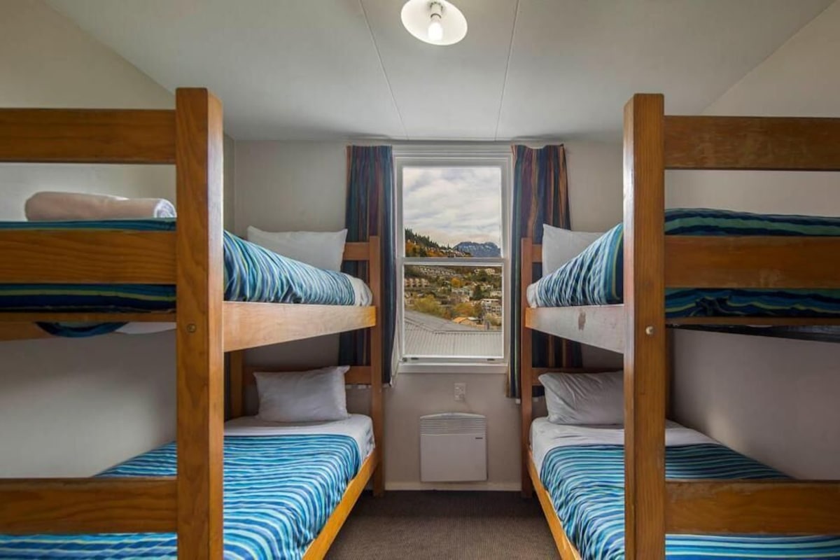 A room with bunk beds, a window with a view, and a ceiling light.