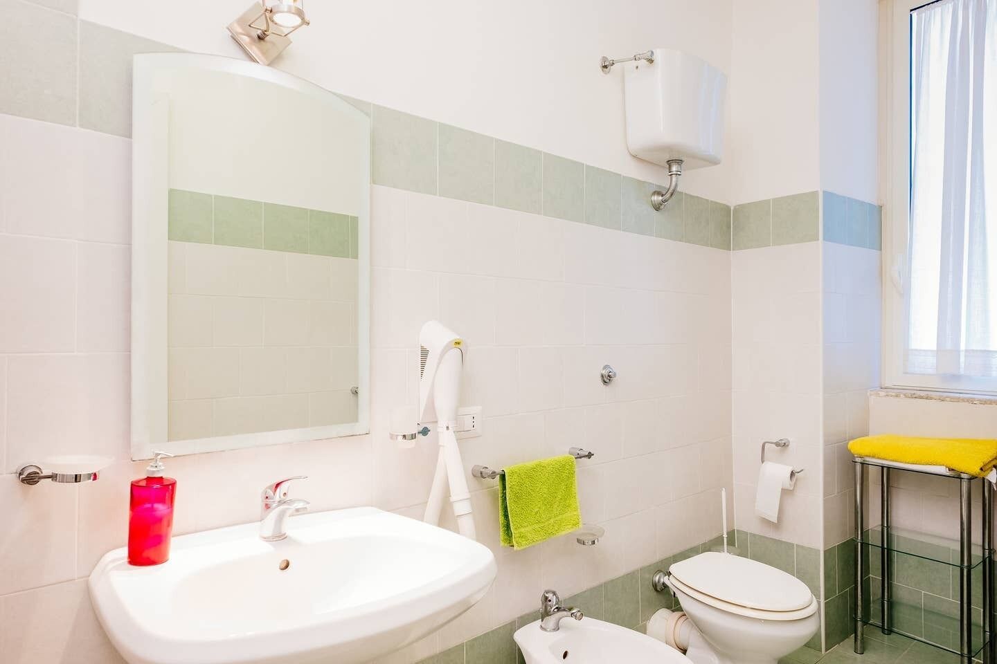 Un baño con lavamanos blanco, un espejo, inodoro y cabina de ducha de vidrio.