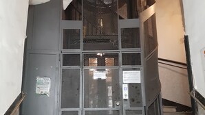 Un escalier avec des rampes en métal et une affiche sur le mur.