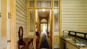 A hallway with wooden flooring, a black carpeted area, and a bookcase filled with books. - Bowen Terrace Accommodation (New Farm)
