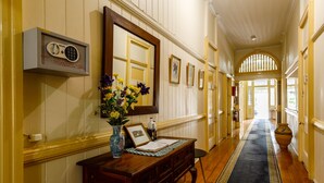A hallway with a wooden bench, a vase with flowers, a framed picture, and a wall-mounted safe. - Bowen Terrace Accommodation (New Farm)