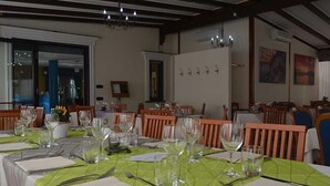 A dining area with tables set for a meal, featuring green tablecloths and wooden chairs. - Costa Hotel (Pompei)