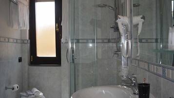 A modern bathroom with a glass shower enclosure, a white sink, and a hairdryer mounted on the wall.