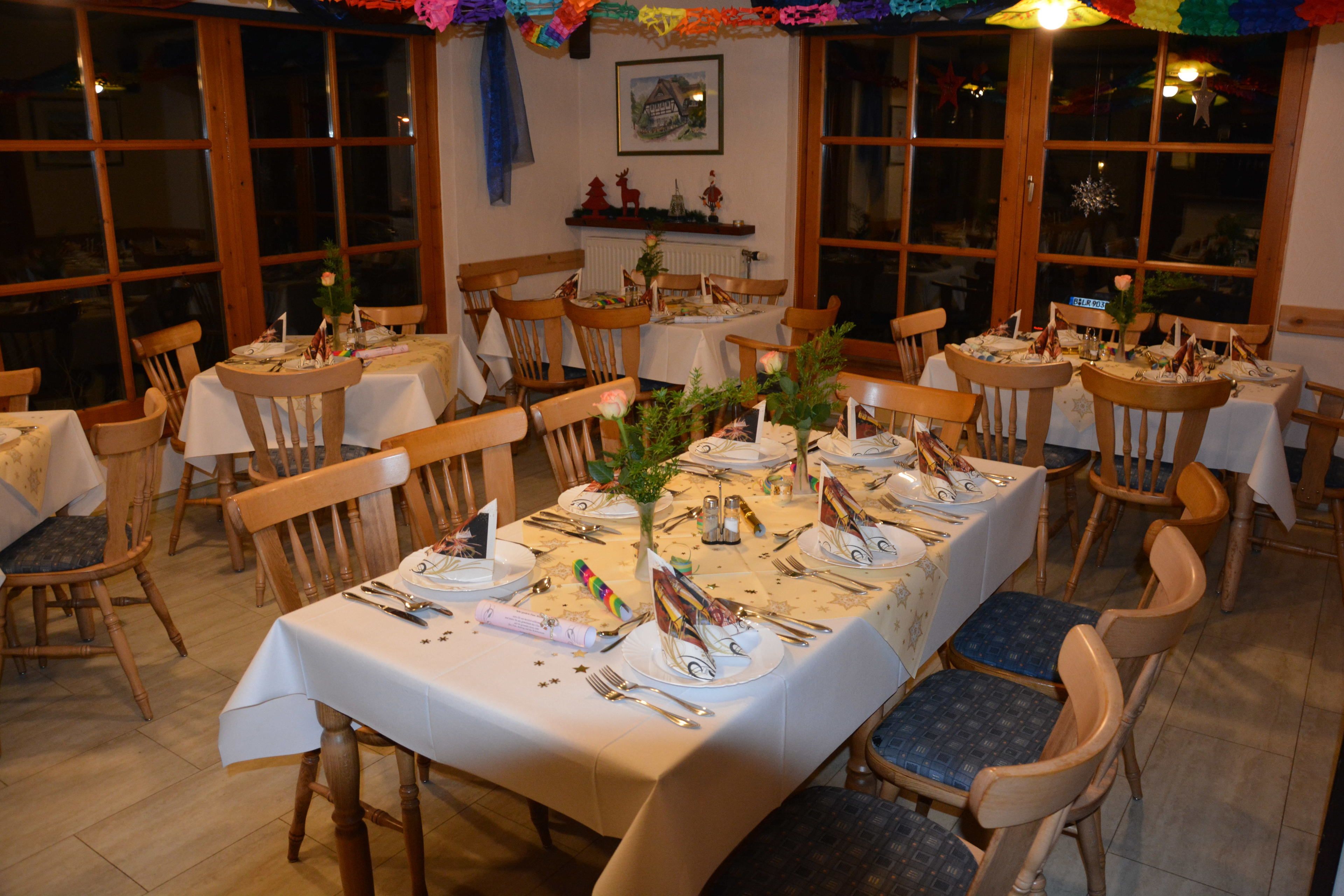 A dining area with multiple tables set for a meal, wooden chairs, and a window view.