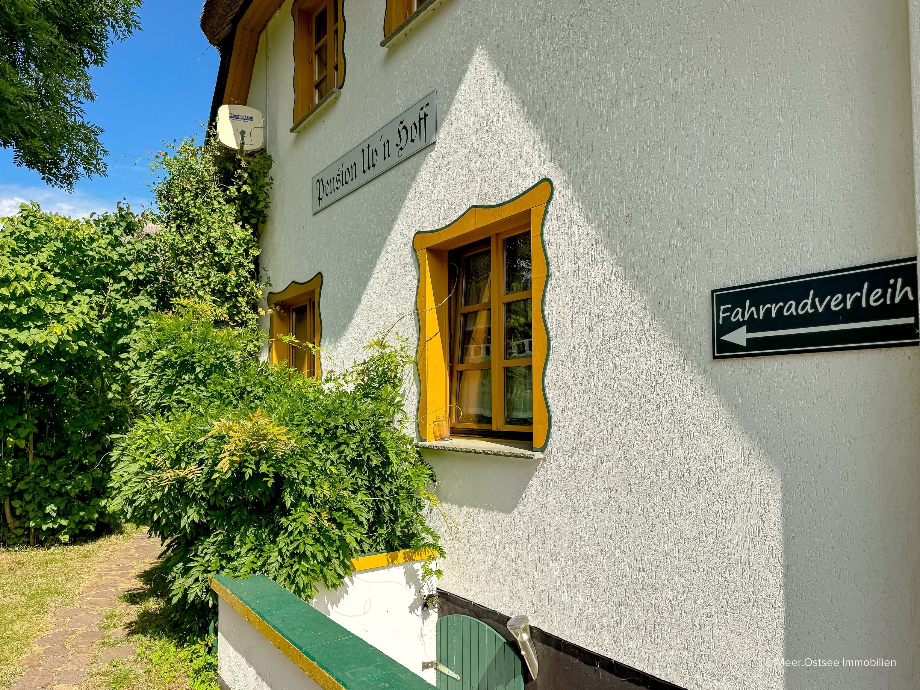 A building with a white exterior, yellow window frames, and a sign indicating 'Fahradverleih.'