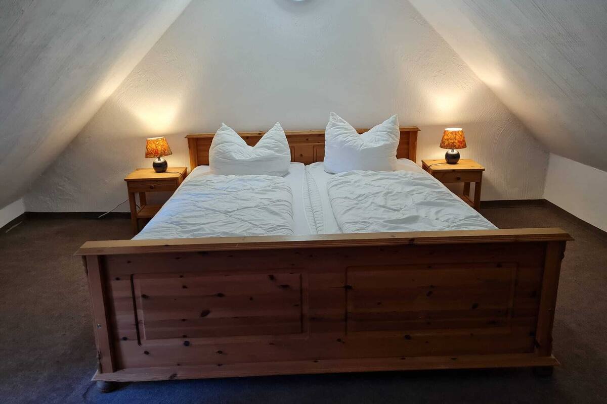 A bedroom with a wooden bed, two bedside tables with lamps, and a skylight.