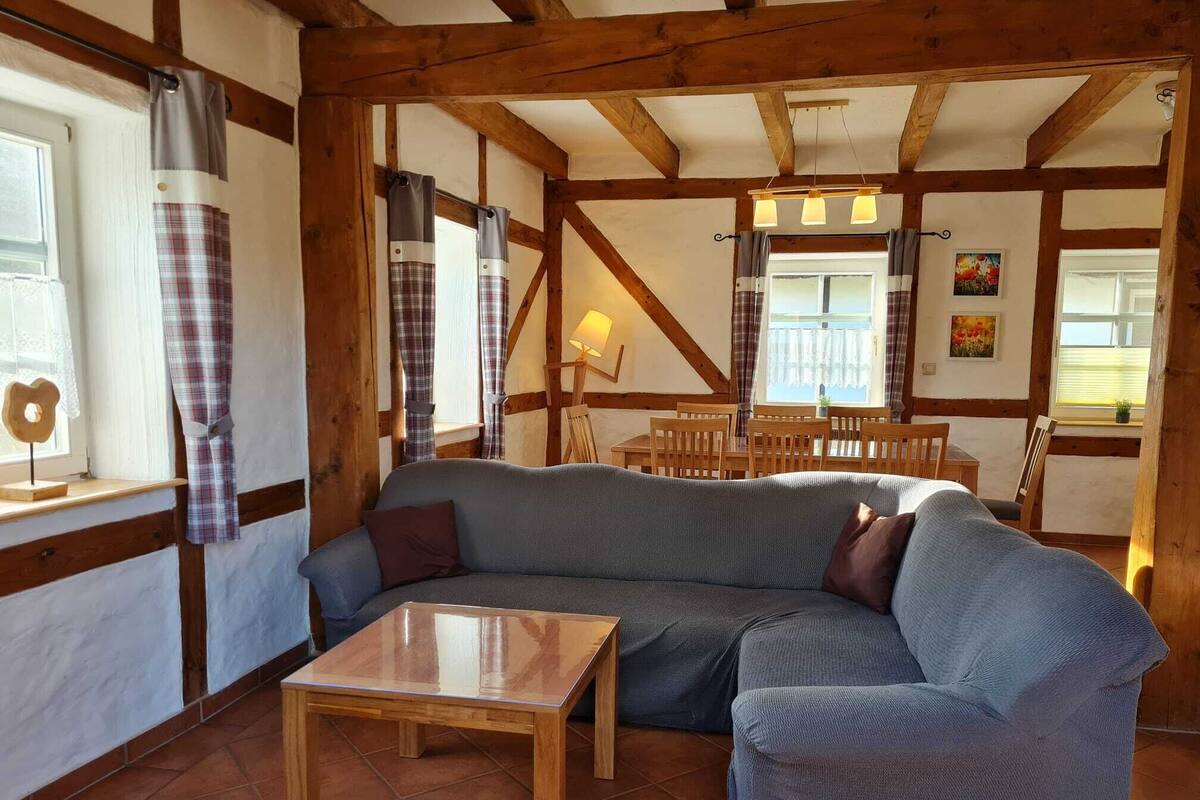 A cozy living room with a grey sectional sofa, a wooden coffee table, and a dining area with wooden chairs and a table.