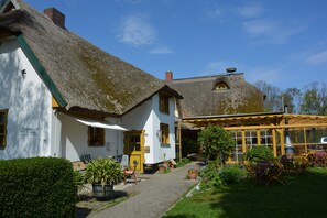 A traditional house with a thatched roof, a small garden, and outdoor seating area. - Reethäuser auf Rügen (Mönchgut-Granitz)