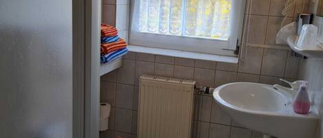 A small bathroom with a toilet, a sink, and a window.