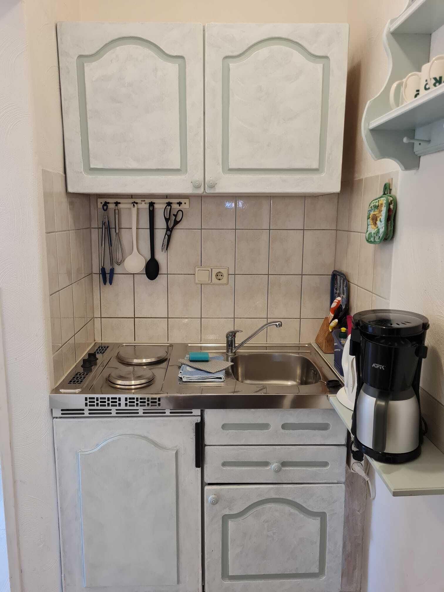 Kompakti keittiö, jossa on sisäänrakennettu liesi, pesuallas ja kahvinkeitin.