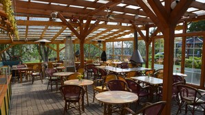 An indoor dining area with wooden tables and chairs, large windows, and a brick floor. - Reethäuser auf Rügen (Mönchgut-Granitz)