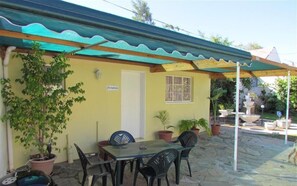A patio area with a table and chairs, potted plants, and a covered seating area. - Stemar Self Catering Guest House (Graaff-Reinet)