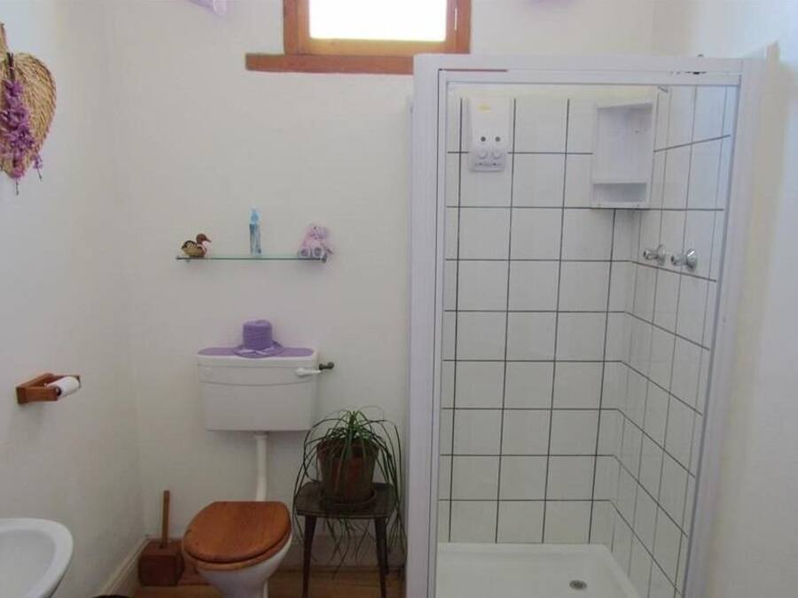 Une salle de bain équipée de toilettes, d’un lavabo, d’une douche et d’une petite étagère où sont rangés les articles de toilette.