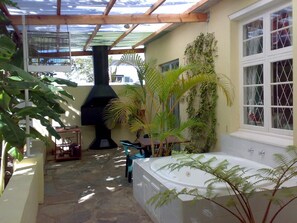 A patio area with a stone floor, a black barbecue grill, a white bathtub, and potted plants. - Stemar Self Catering Guest House (Graaff-Reinet)
