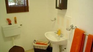Et badeværelse med toilet, håndvask og et lille vindue.