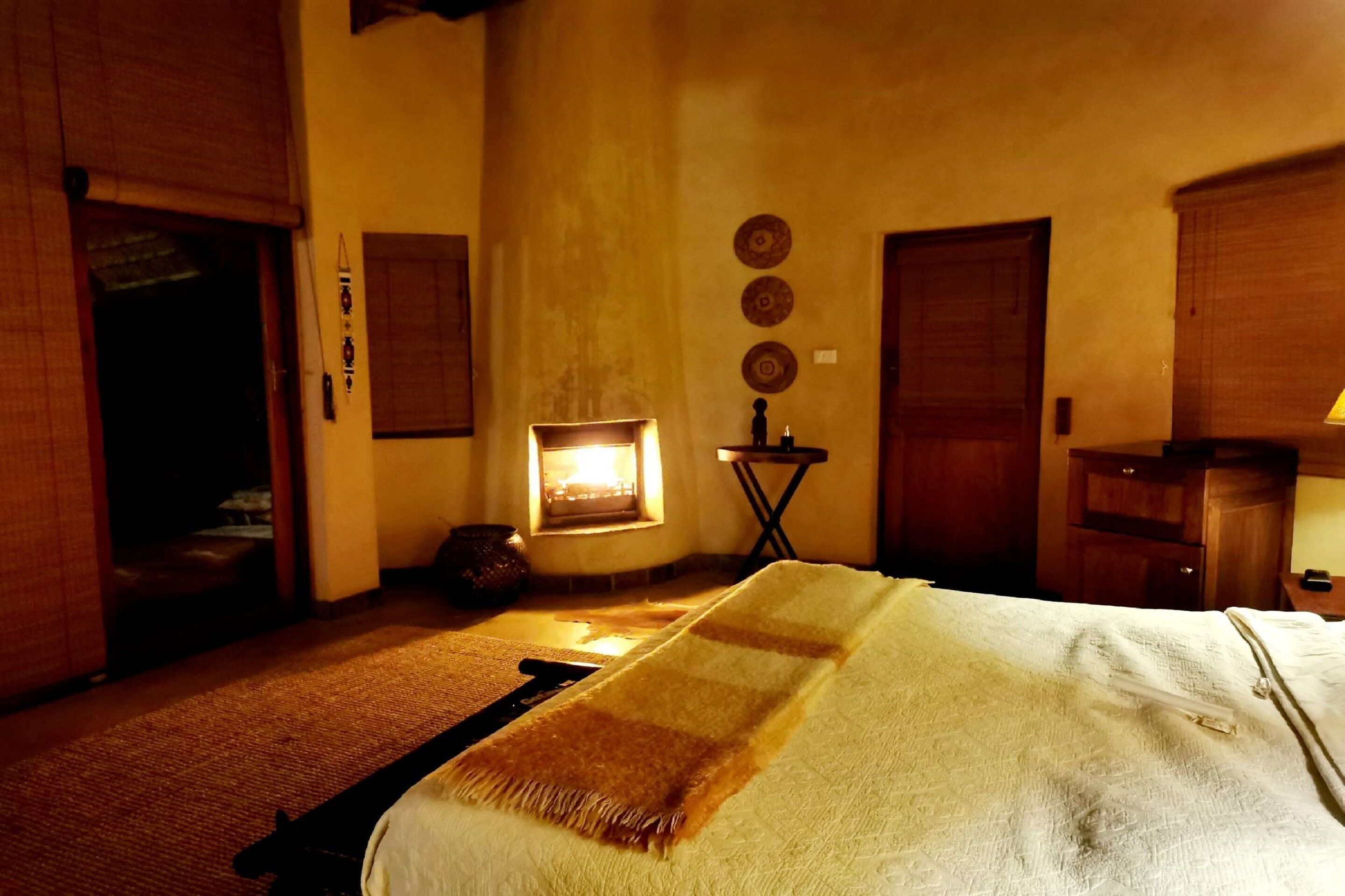 A room with a bed, a small table, a chair, and a window with a view of the outside.