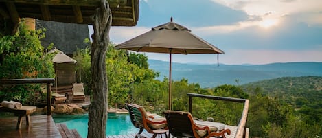 Una piscina al aire libre, sombrillas, sillones reclinables de piscina