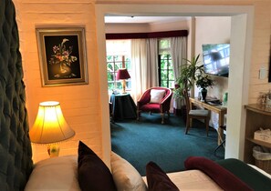 A hotel room with a bed, a desk with a computer, a chair, a TV, and a window with curtains.