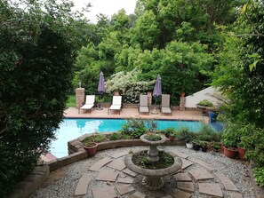 A pool area with lounge chairs and a stone fountain. - Edenwood Guest House (George)