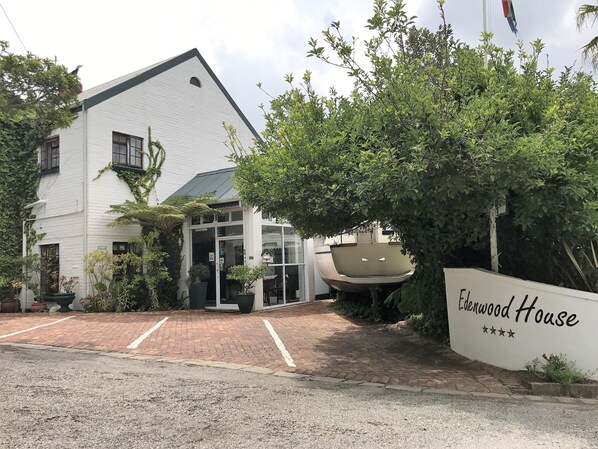 A white building with a sloped roof and a glass entrance. There is a sign that reads "Ladenwood House" with a five-star rating. - Edenwood Guest House (George)