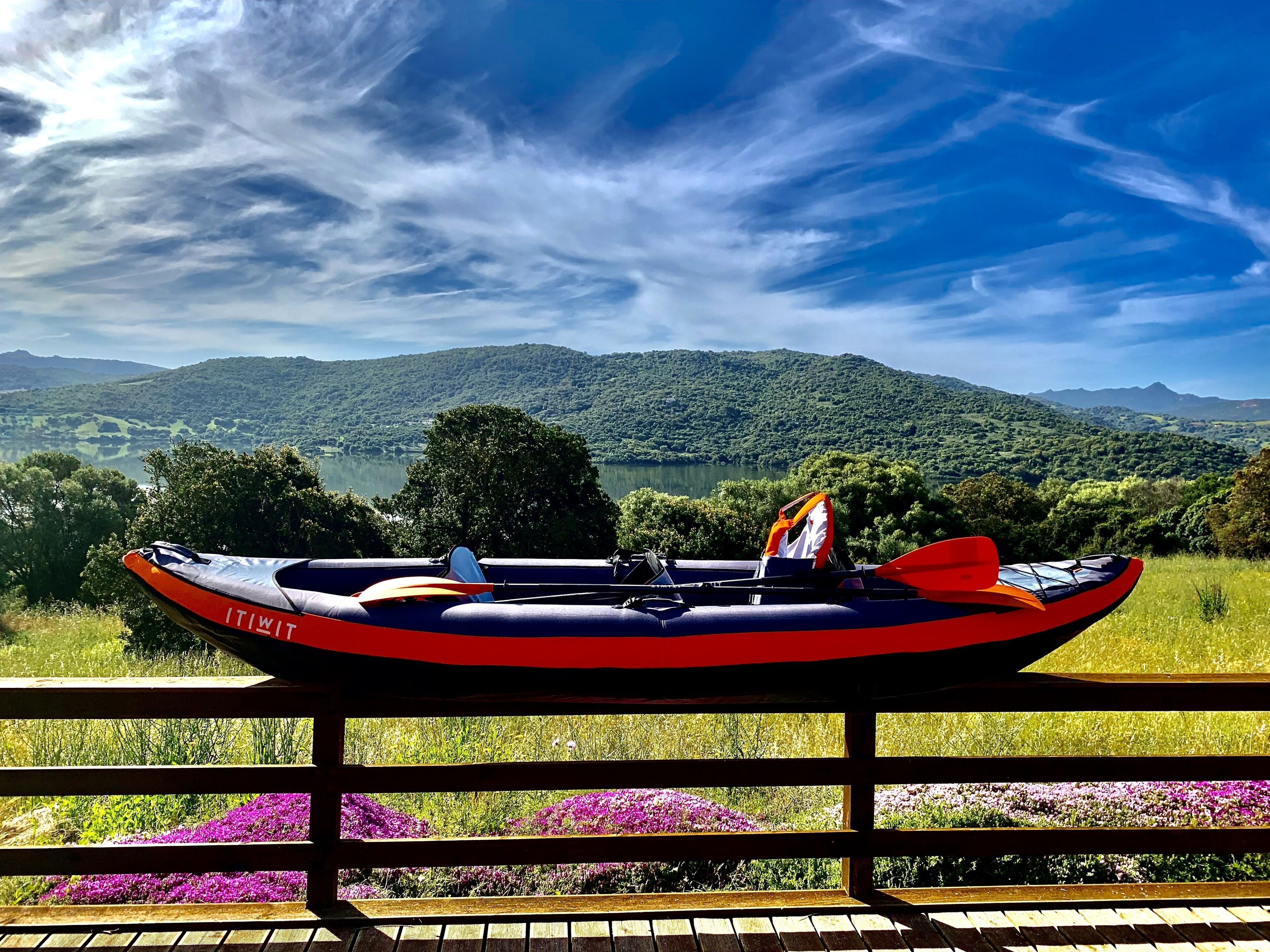 A rowboat on a wooden dock with a view of a lake and mountains.