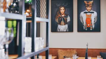 Ein Restaurantinnenraum mit einem Holztisch, gedeckt für zwei Personen, einer gepolsterten Bank und gerahmten Kunstwerken an der Wand.
