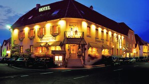 A hotel with a traditional European architectural style, featuring a prominent entrance with a staircase, multiple windows with shutters, and a sign indicating it is a hotel. - Hotel Hanauerhof (Appenweier)