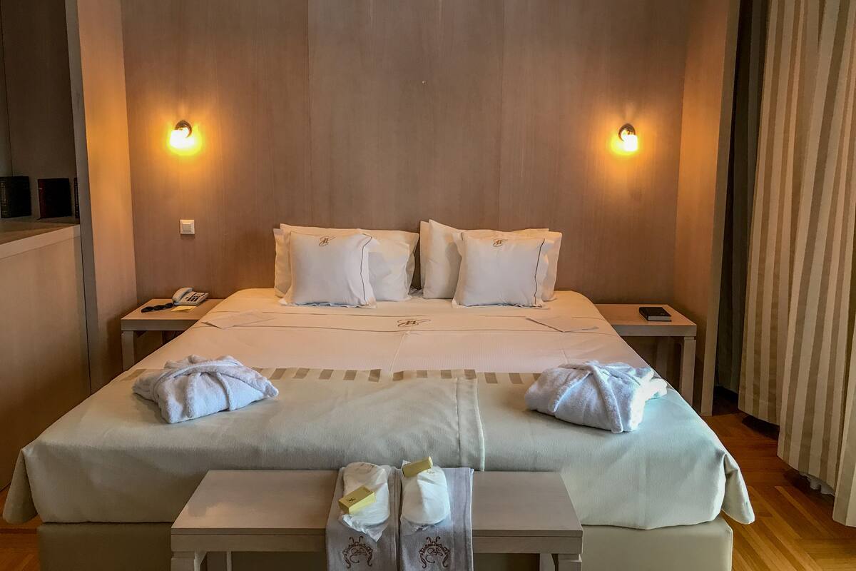 A hotel room with a large bed, two bedside tables, a bedside phone, and two wall-mounted lights.