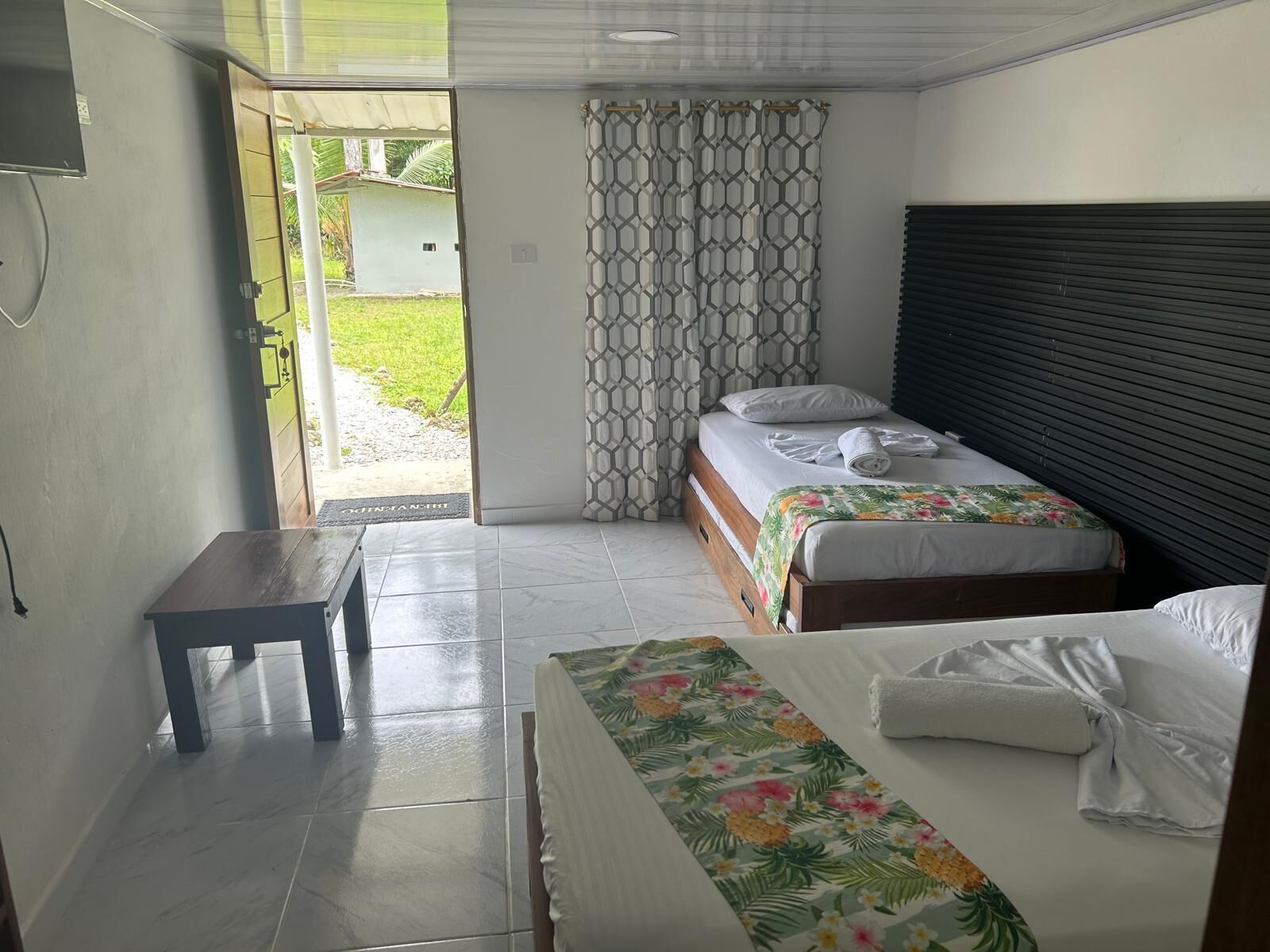 Habitació d'hotel amb dos llits, una taula petita i vista exterior.