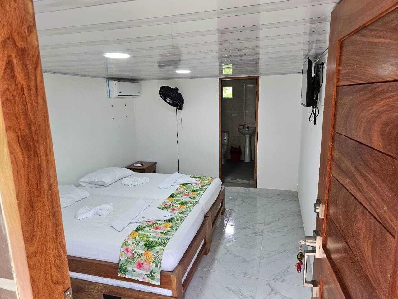 Ein Schlafzimmer mit einem Bett, einer Holztür und einem kleinen Nachttisch.