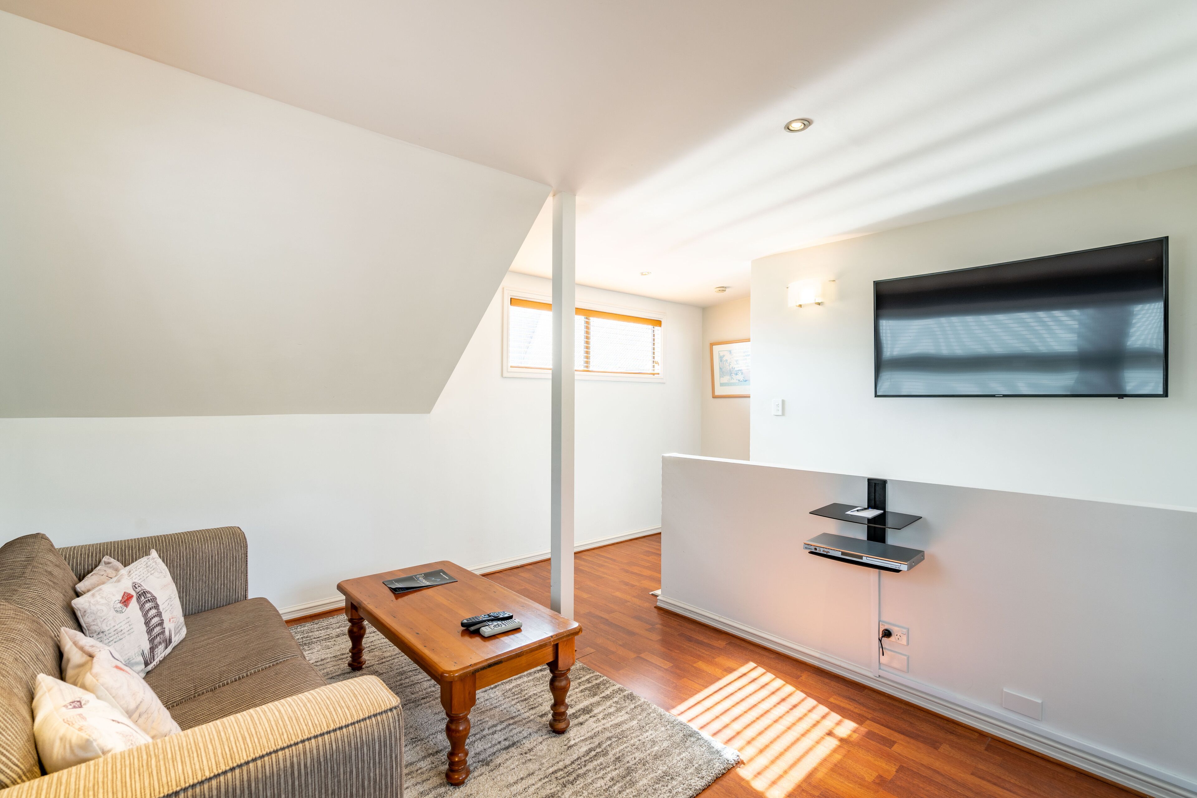 A modern living room with a sofa, a coffee table, and a flat-screen TV mounted on the wall.