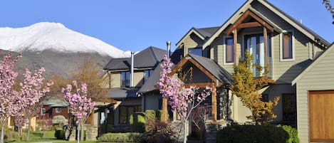 A modern two-story house with a stone foundation, large windows, and a prominent chimney.