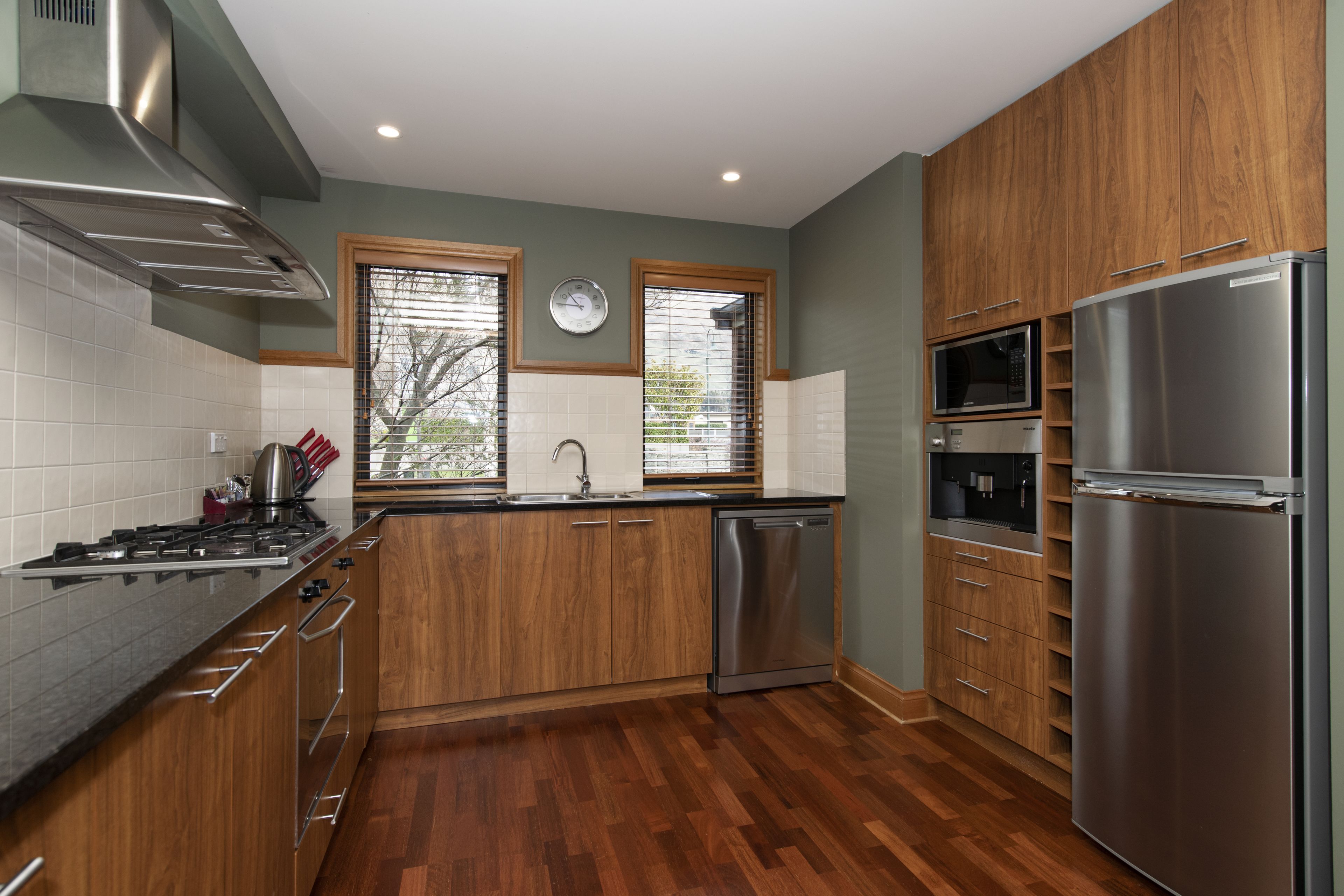 A modern kitchen with wooden cabinets, stainless steel appliances, and a tiled backsplash.