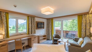 A hotel room with a bed, desk, chair, sofa, and a TV.