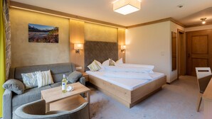 A hotel room with a bed, a sofa, a small table, and a chair.