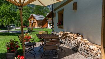 Eine Terrasse mit Holztisch und -stühlen, einer Steinmauer und einem Holzstapel.