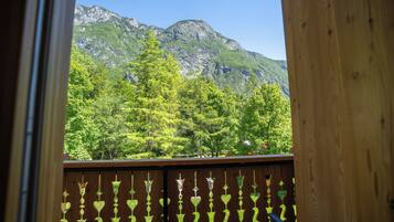 A wooden balcony with heart-shaped cutouts, overlooking a forested mountain.