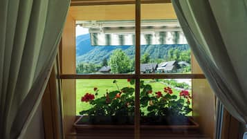A window with a view of a green landscape and a house.