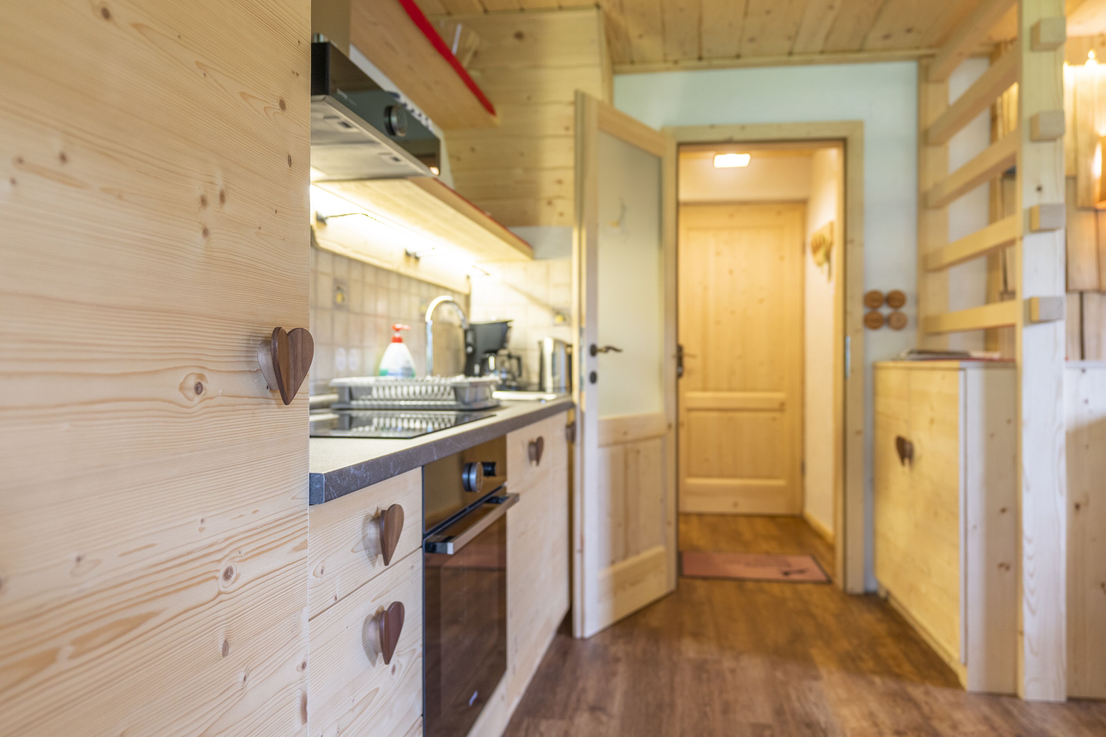 Un intérieur en bois comprenant un espace cuisine avec un fourneau, un évier et des placards.