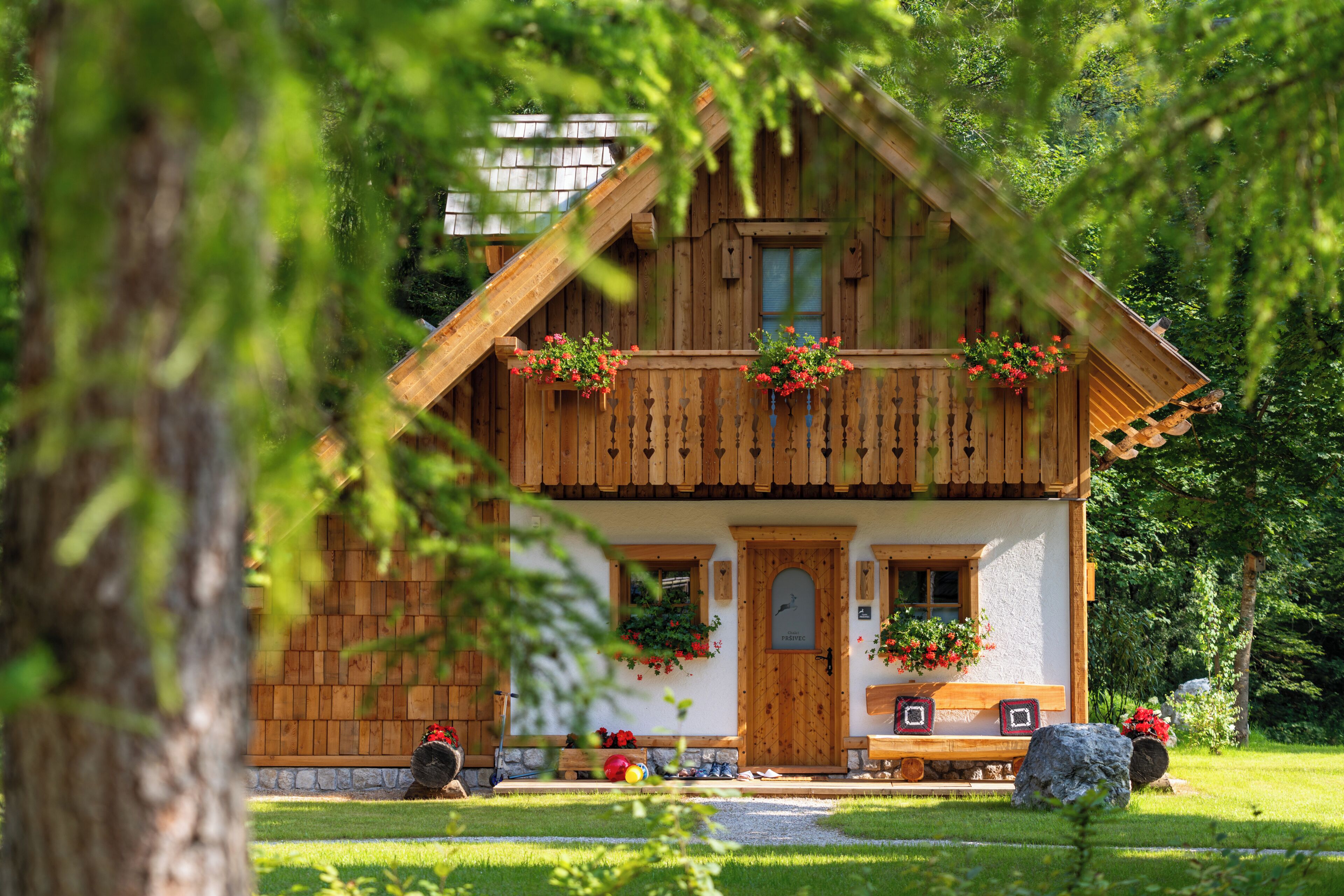 Una cabaña de madera con balcón, puerta principal y un pequeño porche.